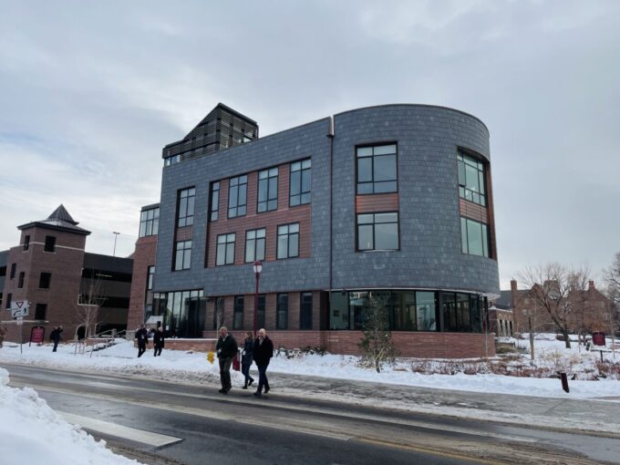 The Burwell Center building is shown from across the street on a winter's day with snow on the ground. The building is at least three stories tall, with a penthouse structure on the room to the left side of the image. The facade of the building is curved to the right side of the image.