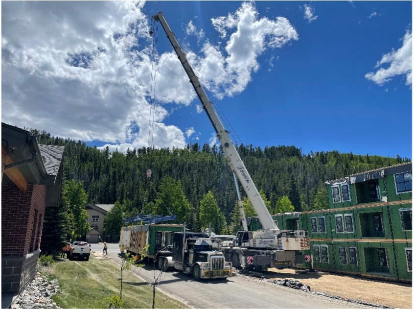 Volumetric construction process photo: module being lifted by a crane.