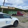 EVstudio's white company vehicle is shown in the foreground of the construction site for the Justice Center Apartments in Breckenridge, CO. Modular construction of volumetric design is shown in the background.