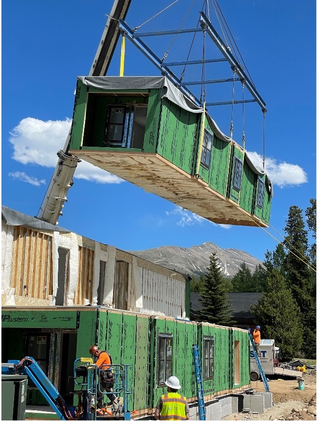 Volumetric construction process photo: module being lifted by a crane.