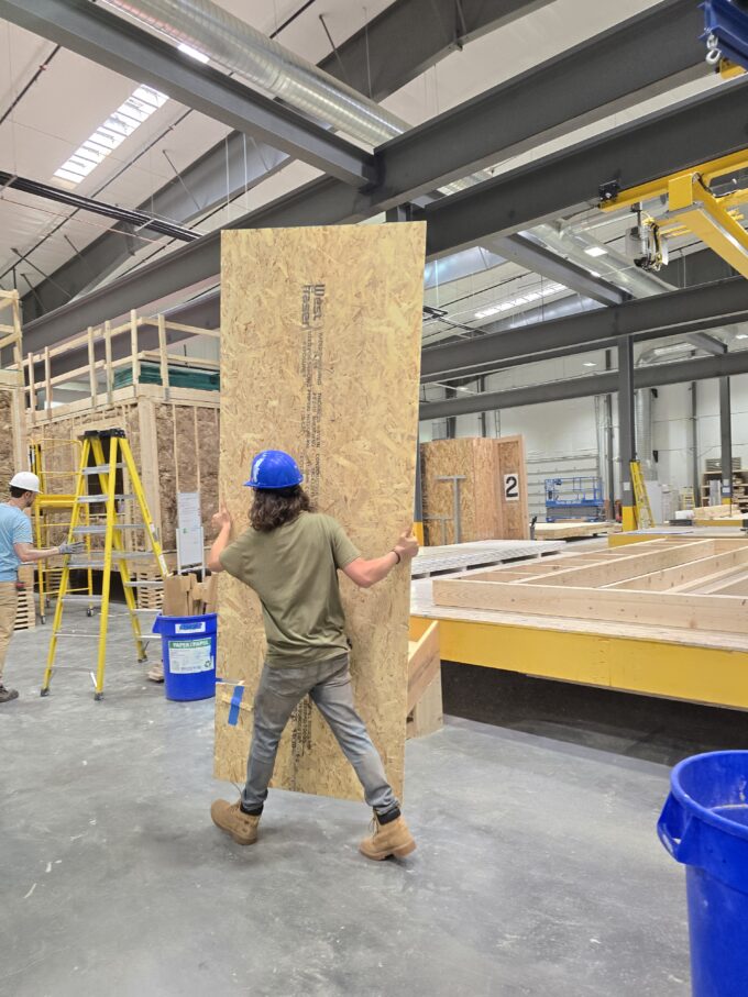 One EVstudio employee carries a piece of plywood through the Boulder MOD factory.