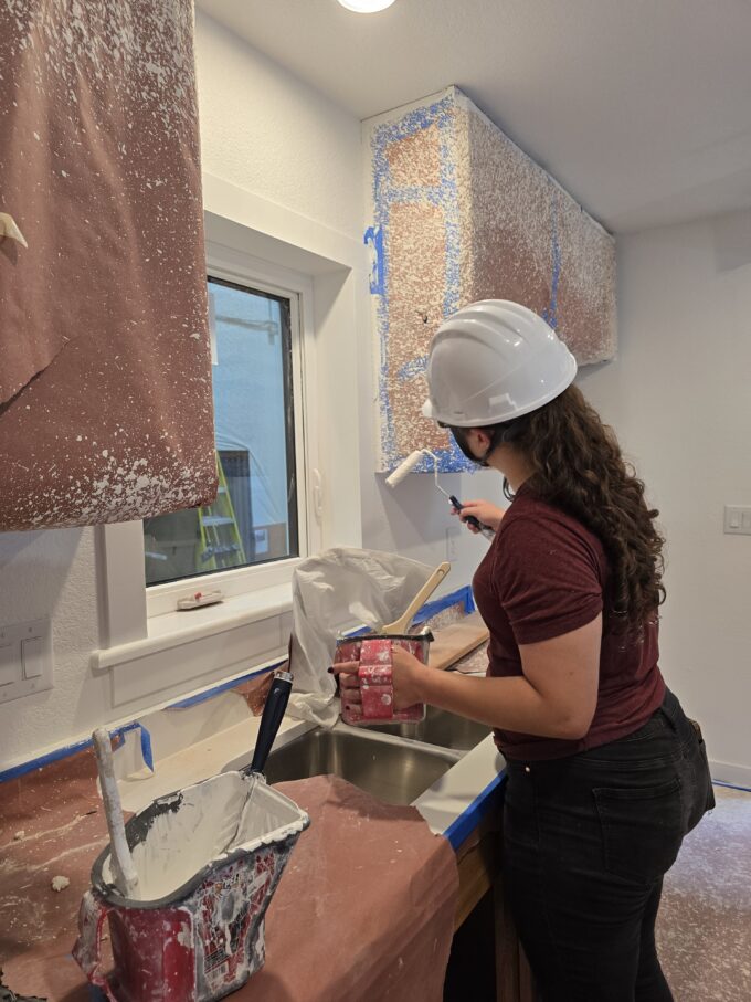 One EVstudio employee paints a wall in one of the modular homes at Boulder MOD factory