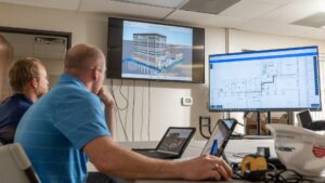 Engineers looking at two different screens with new build technology