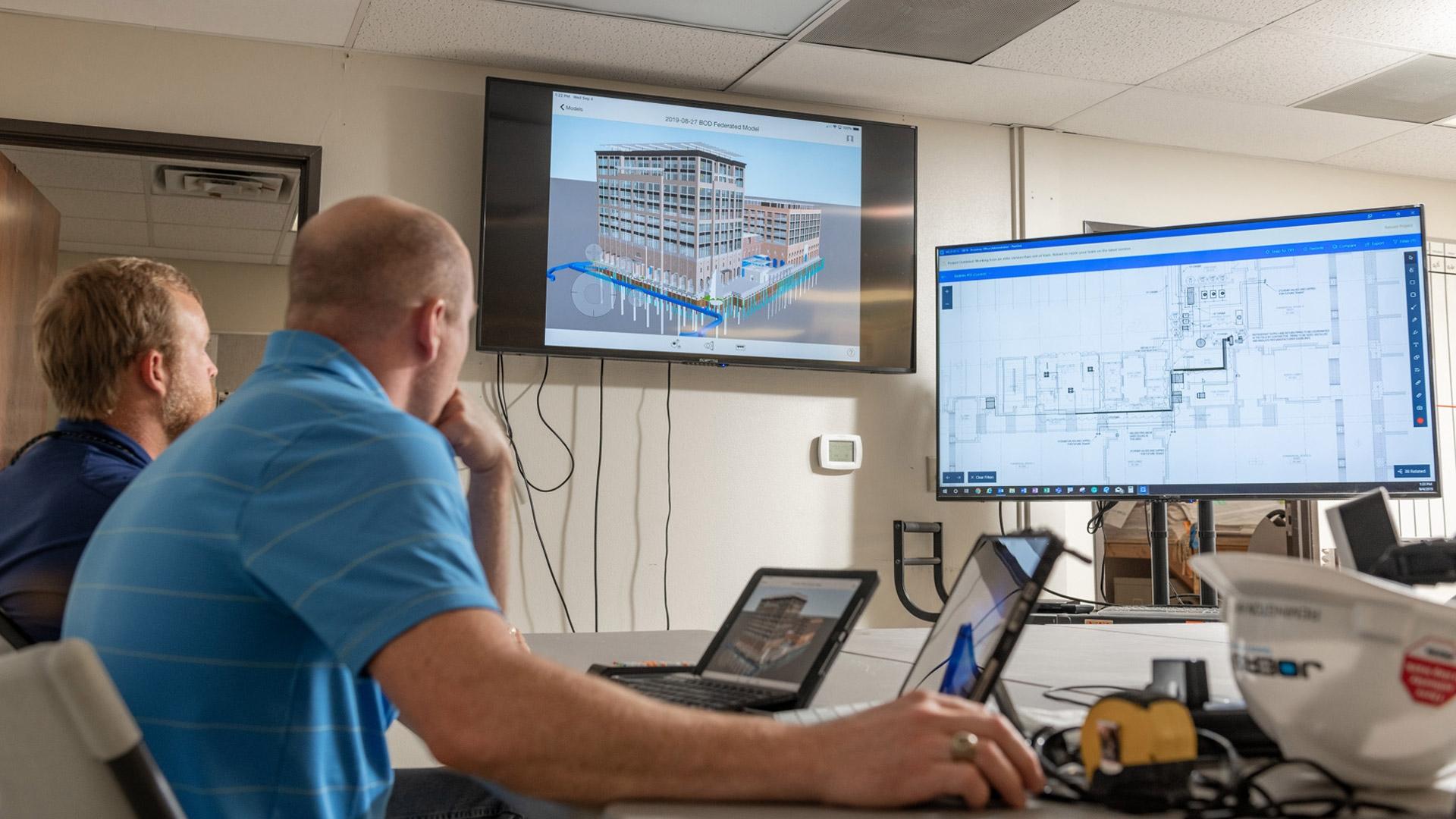 Engineers looking at two different screens with new build technology 