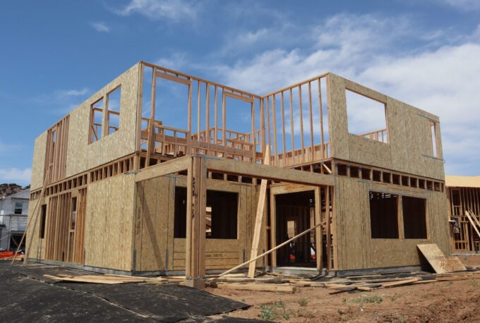 Two-story residential home under construction showing OSB shear wall sheathing and wood framing