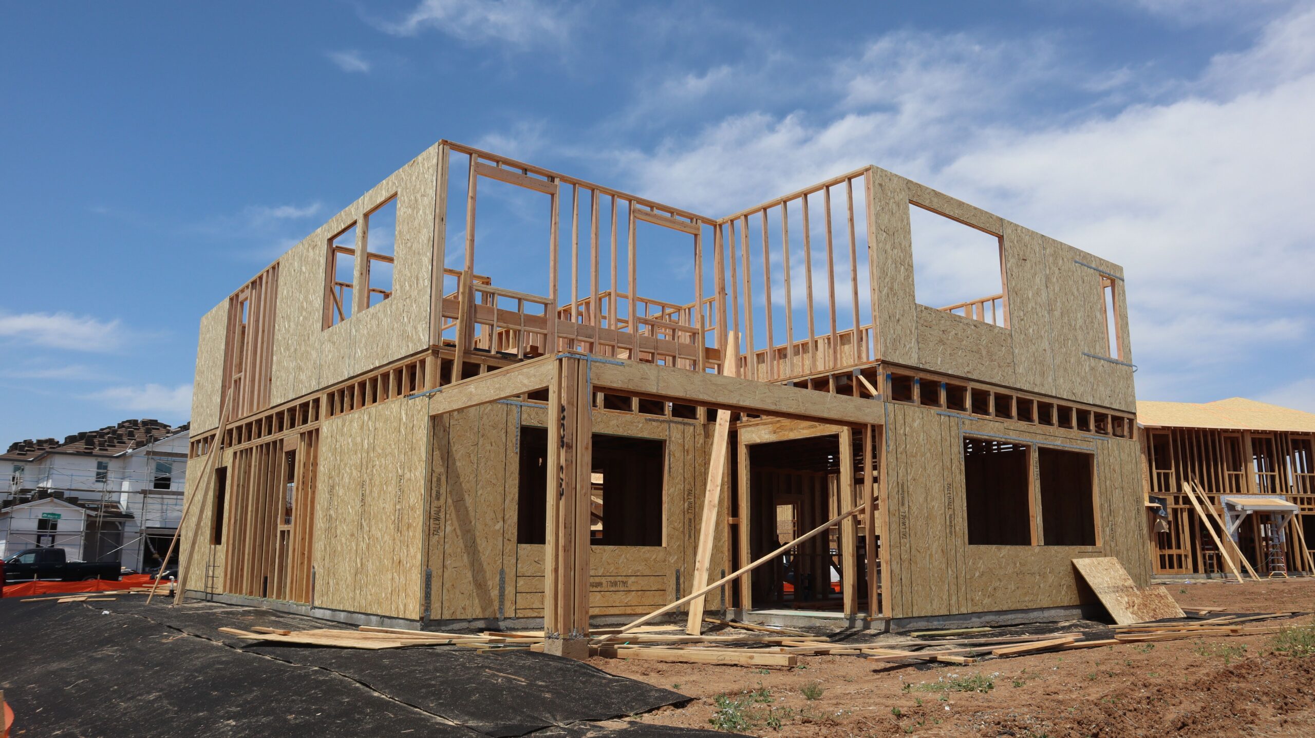 Two-story residential home under construction showing OSB shear wall sheathing and wood framing