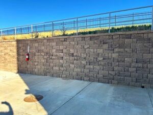 Retaining wall with sidewalk at the base and a railing at the top.