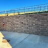 Retaining wall with sidewalk at the base and a railing at the top.