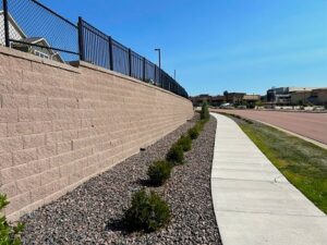 MSE Retaining wall with a sidewalk at the base and guardrail fence at the top.
