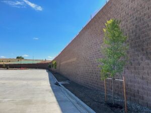 Tall retaining wall on commerical site with parking lot and drain at the base.